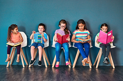 Buy stock photo Kids, learning and row with books in studio for knowledge, development and studying for test. Chair, children and students reading with youth for scholarship, school education and academic growth