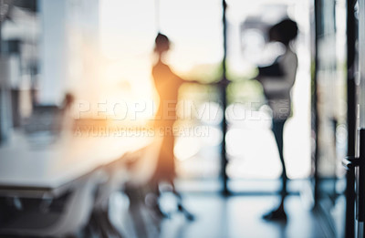 Buy stock photo Defocused shot of two businesswomen shaking hands in an office