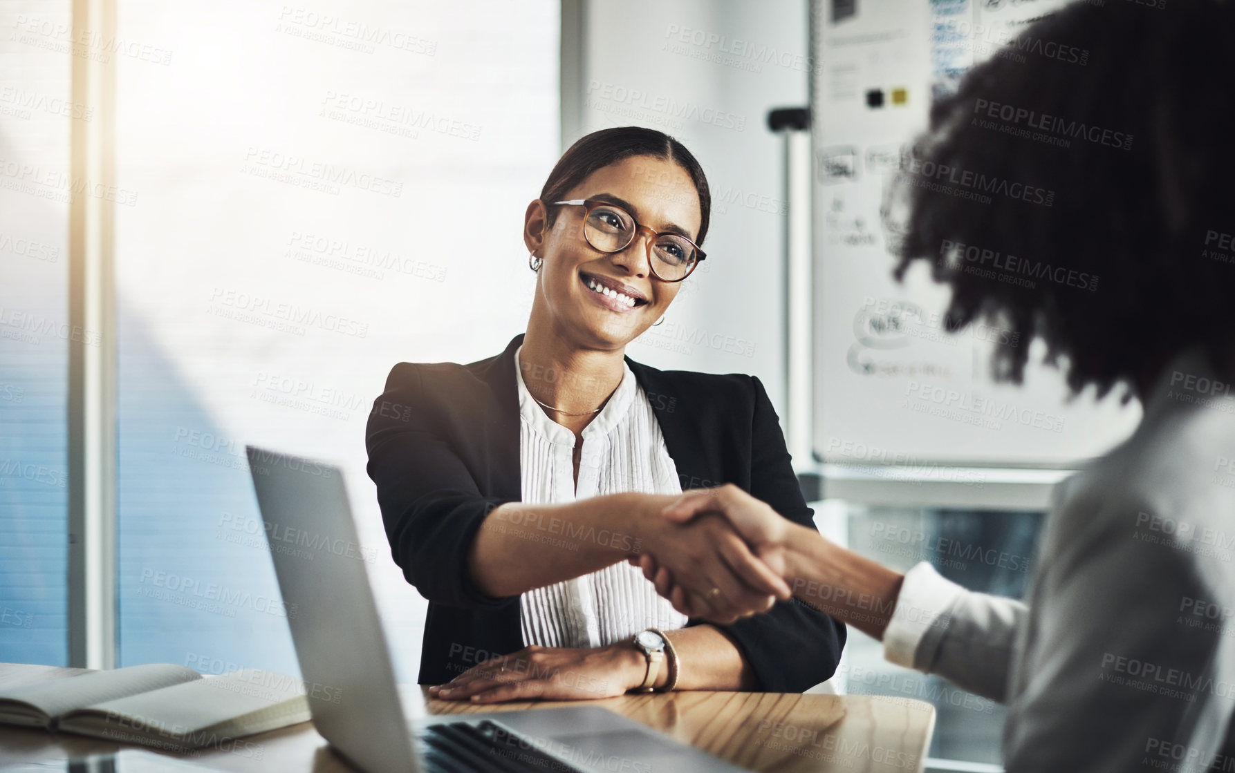 Buy stock photo Shot of two businesswomen shaking hands in an office