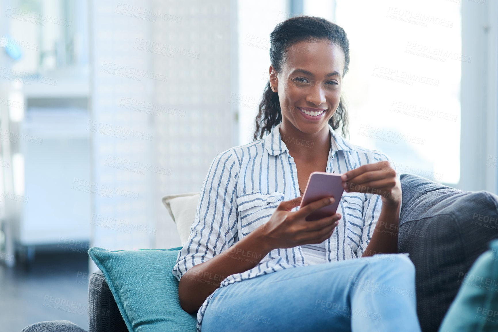 Buy stock photo Portrait of a young woman texting on a cellphone at home