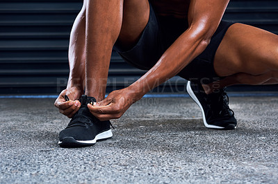 Buy stock photo Shot of an unrecognizable man tying his shoelaces in the middle of his exercise routine