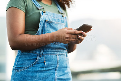 Buy stock photo Shot of an unrecognizable young woman sending a text message while standing outside