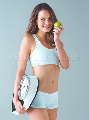 Buy stock photo Studio shot of a healthy young woman holding a scale and an apple against a grey background