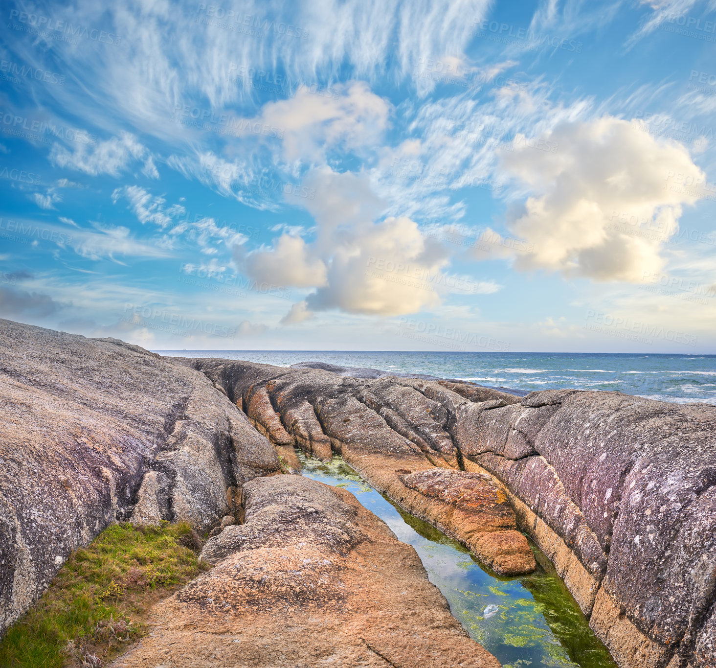 Buy stock photo Ocean view on a shallow rocky shoreline with Lion's Head, Table Mountain National Park in Cape Town, South Africa in the background. Quiet calm beach during sunset on a beautiful summer day