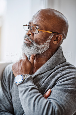 Buy stock photo Shot of a handsome senior man looking thoughtful while relaxing at home