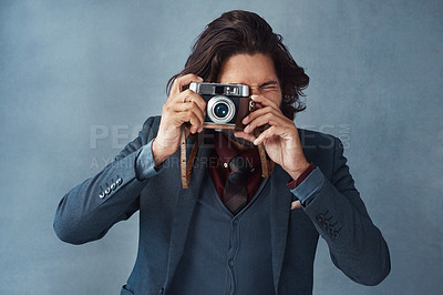 Buy stock photo Studio shot of a stylishly dressed handsome young man taking a picture with a vintage camera