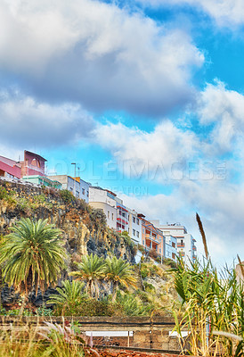 Buy stock photo Scenic view of palm trees, vibrant houses and blue sky with clouds and copy space in Santa Cruz de La Palma, Spain. Tropical landscape of infrastructure and architecture buildings in tourism resort