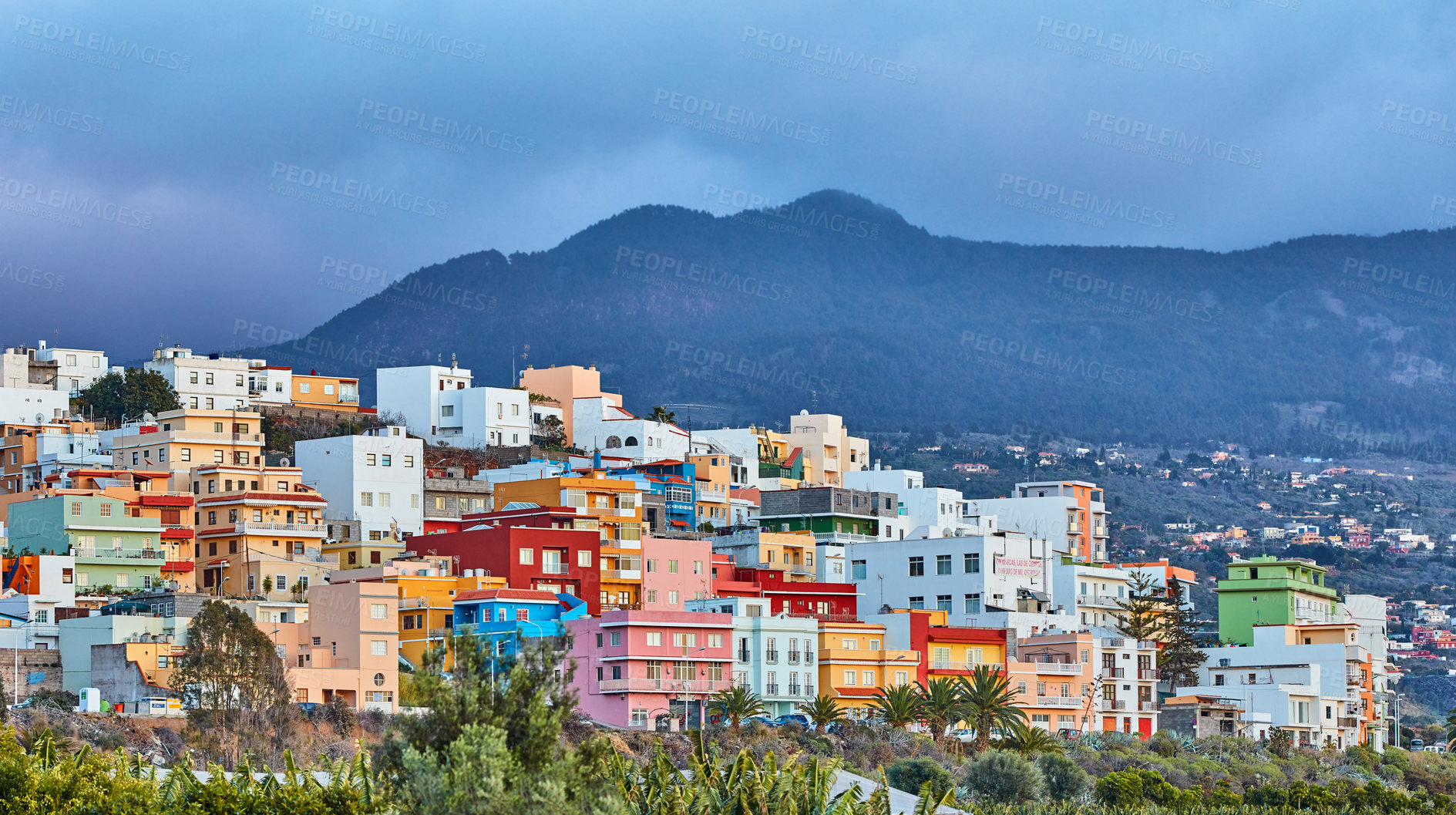 Buy stock photo Colorful buildings in Santa Cruz de La Palma with copy space. Beautiful cityscape with bright colors mountains and overcast clouds. A vibrant holiday or vacation destination on the hillside