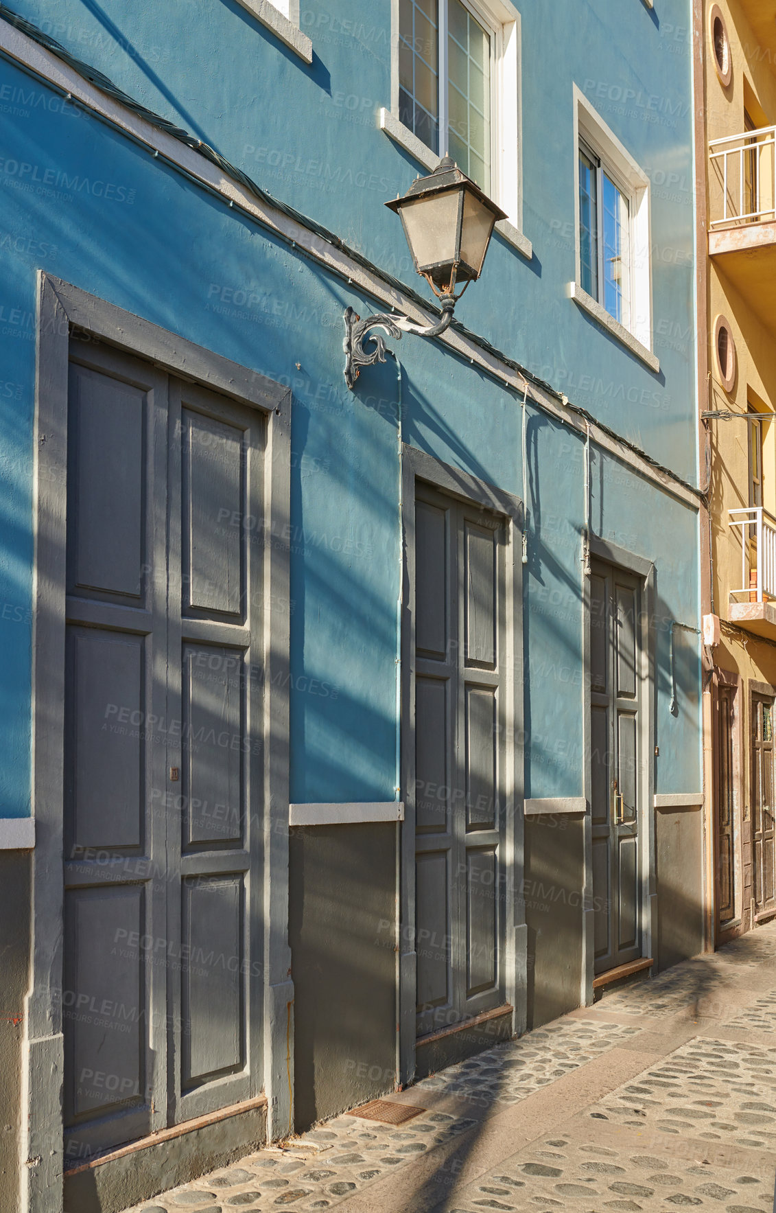 Buy stock photo Houses or homes built in vintage architecture design in a small town village. Vibrant city with cobble stone road or street. Blue building with grey doors in the streets of Santa Cruz de La Palma. 