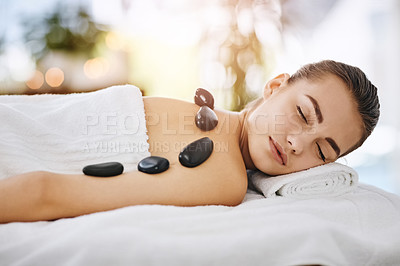 Buy stock photo Hot stone massage, relax and woman in spa, on bed or table for luxury treatment or wellness. Break, face and rock on back of calm customer in health resort for alternative therapy or healing