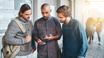 Buy stock photo Shot of a group of young students using a smartphone together outdoors on campus