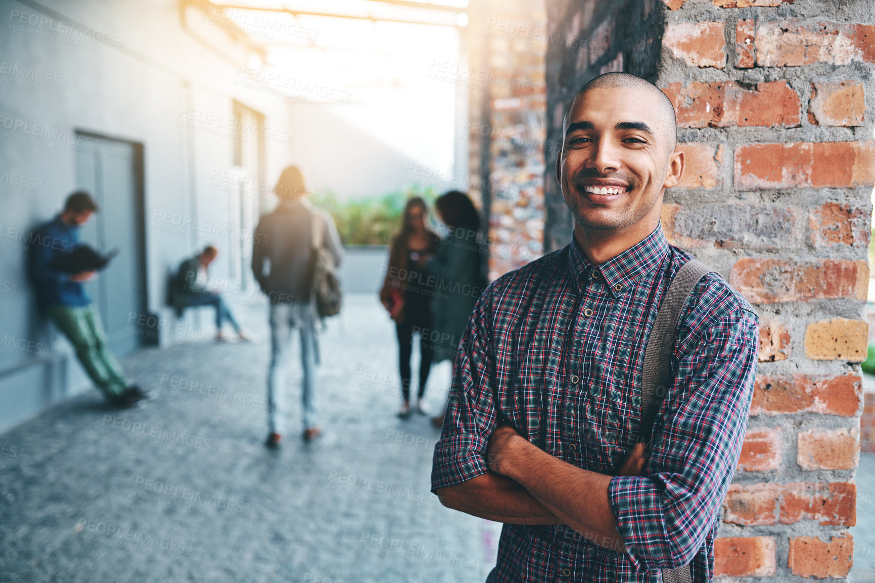 Buy stock photo Portrait, university student and man with arms crossed, brick wall and learning for scholarship with success. Face, happy person or guy with education, pride and knowledge with college and lens flare