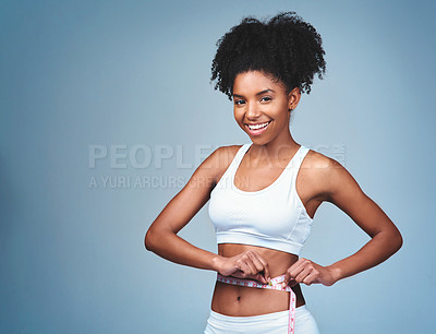 Buy stock photo Shot of an attractive young woman measuring her waist against a grey background