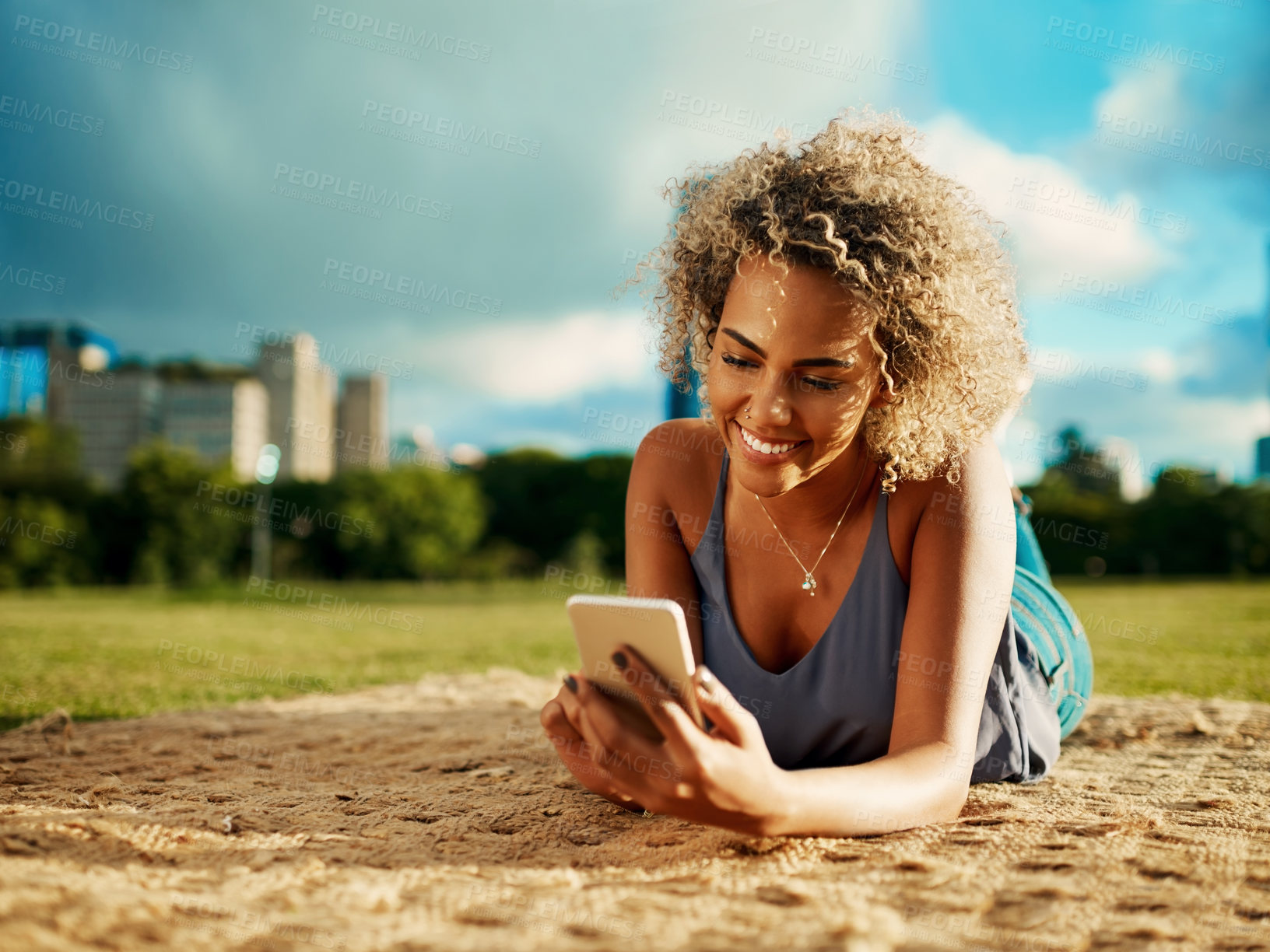 Buy stock photo Phone, relax and smile with woman at park in city on blanket for communication, social media or wellness. App, contact and text message with happy person on grass or lawn for morning or weekend