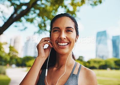 Buy stock photo Cropped shot of an attractive young sportswoman listening to music while working out outdoors in the city