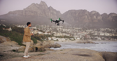 Buy stock photo Full length shot of a young man flying his drone outdoors