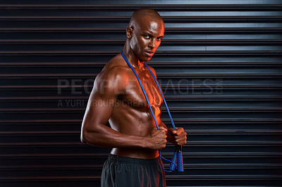 Buy stock photo Studio shot of an athletic young man holding a skipping rope around his shoulders against a grey background