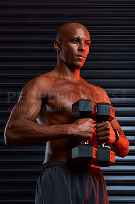 Buy stock photo Studio shot of an athletic young man working out using dumbbells against a grey background