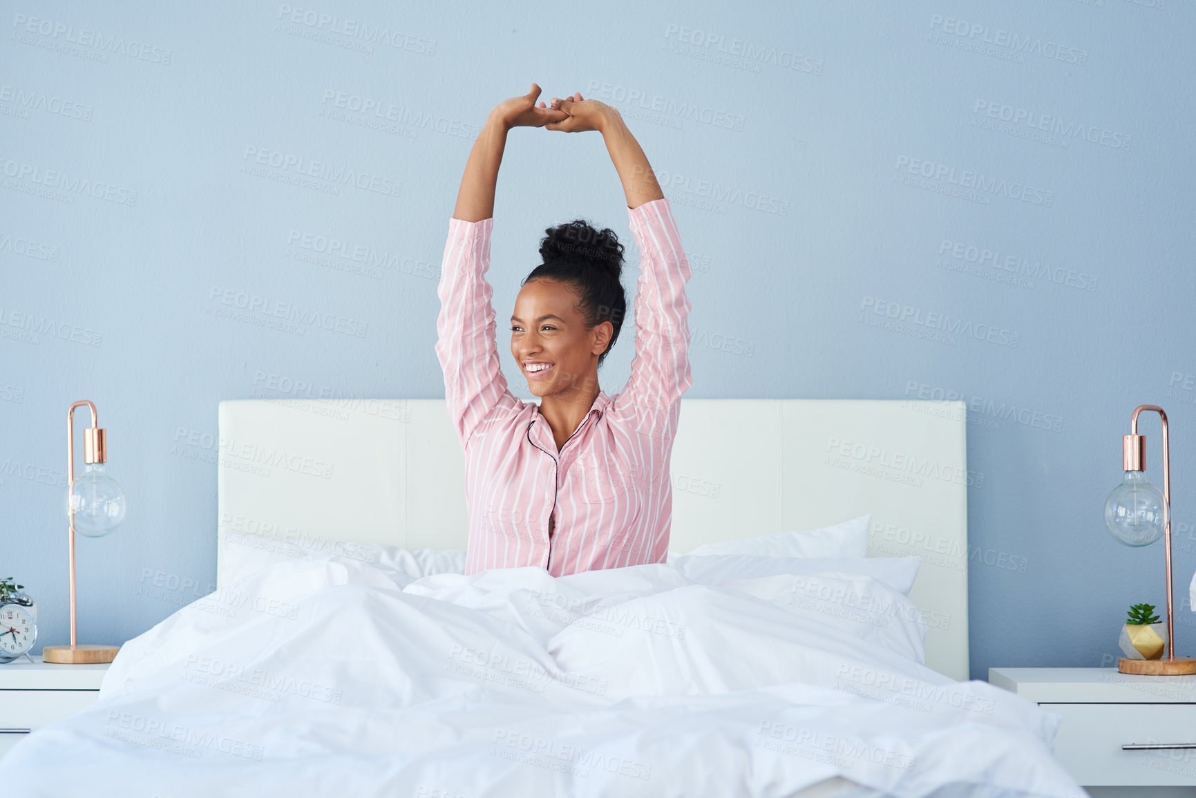 Buy stock photo Shot of an attractive young woman posing with her arms raised in bed at home