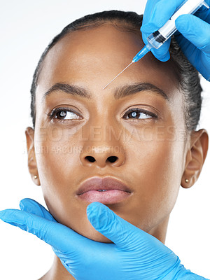 Buy stock photo Studio closeup of an attractive young woman receiving a botox injection in her face while standing against a white background