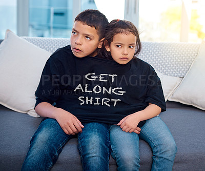 Buy stock photo Upset, siblings and children on sofa in home with funny, comic and silly tshirt for joke. Fight, angry and young boy and girl kids in argument with goofy fashion on couch in living room at house.