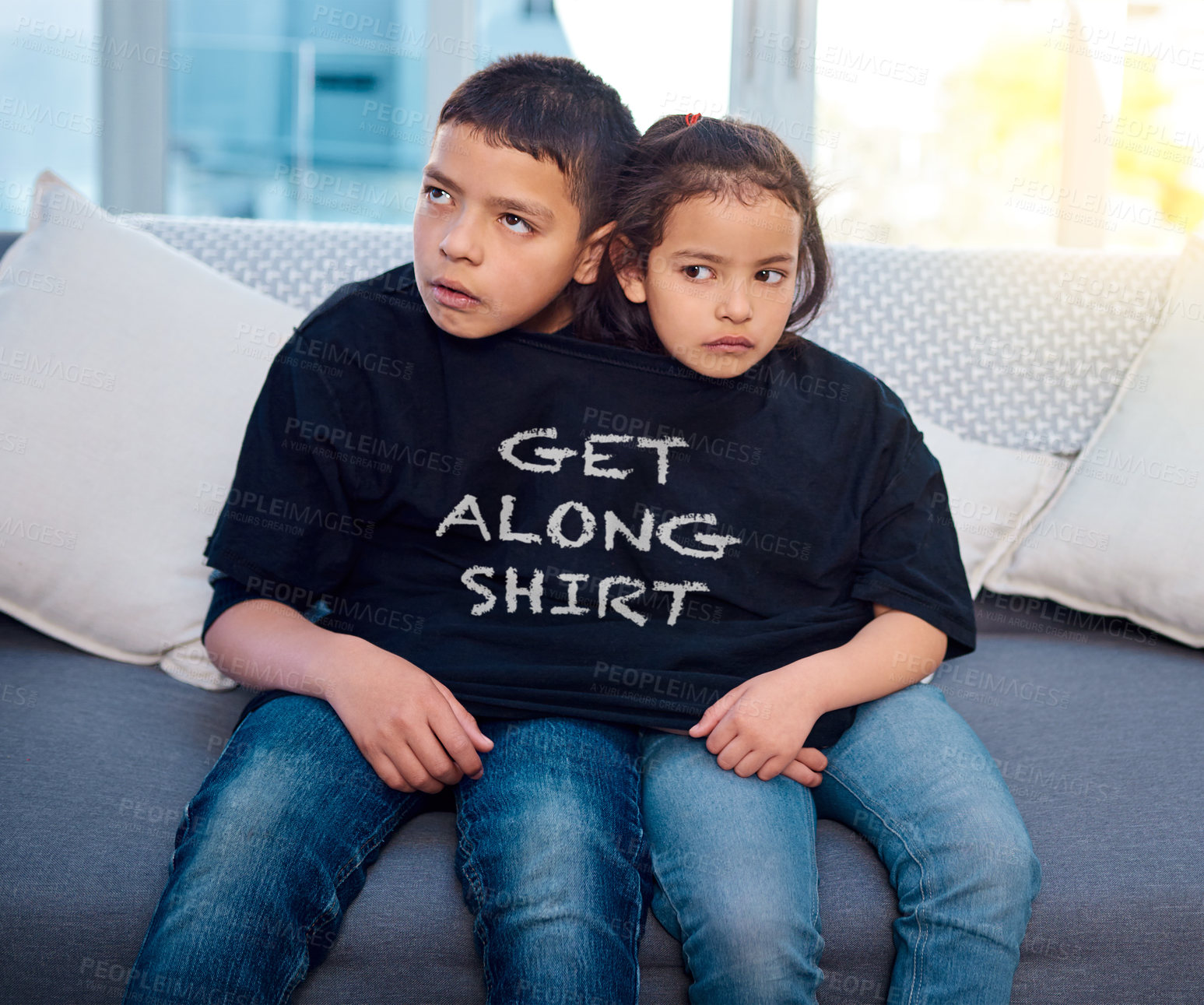 Buy stock photo Upset, siblings and children on sofa in home with funny, comic and silly tshirt for joke. Fight, angry and young boy and girl kids in argument with goofy fashion on couch in living room at house.