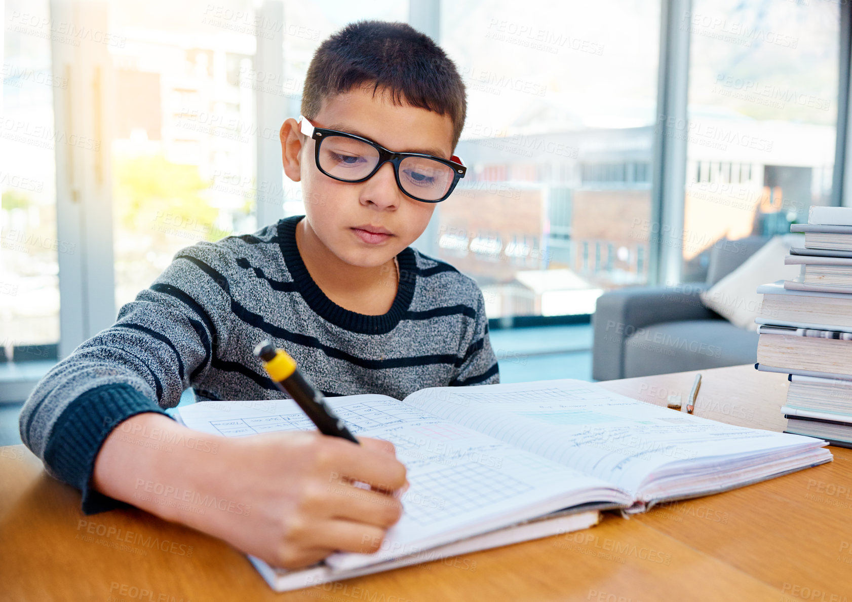 Buy stock photo Boy, student and writing in book for studying, homework or learning in education on table at home. Smart little kid or child busy on mathematics, textbooks or problem solving for study in living room