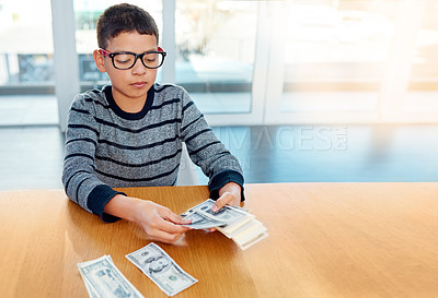 Buy stock photo Shot of a focused young boy counting his money on the dinner table at home
