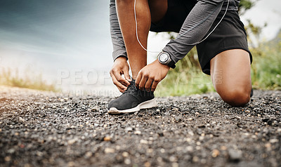 Buy stock photo Closeup shot of a sporty man tying his shoelaces while exercising outdoors
