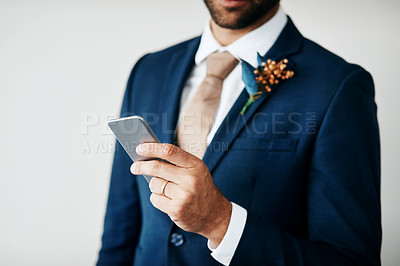 Buy stock photo Cropped studio shot of a stylish young groom holding a cellphone while standing  against a gray background