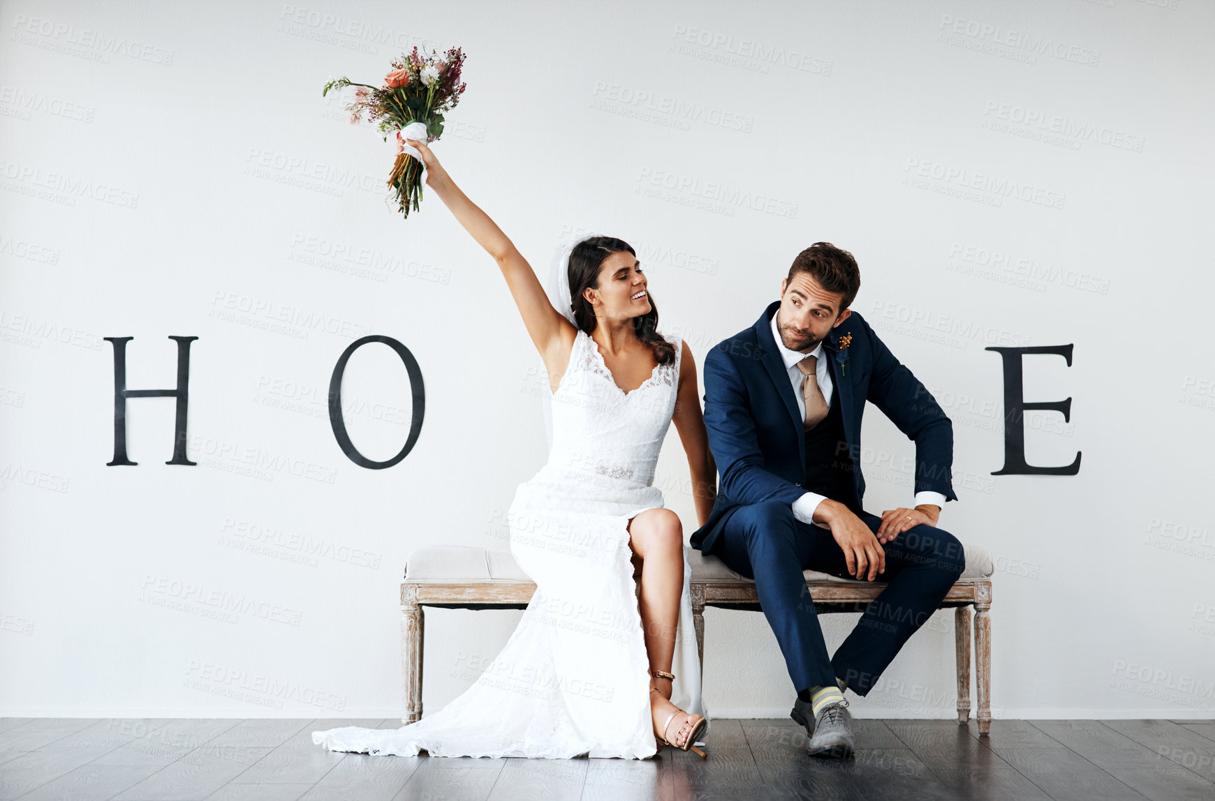 Buy stock photo Concept studio shot of a bride and groom making an V in the word “love” against a wall