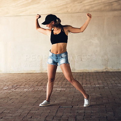 Buy stock photo Full length shot of an attractive young female street dancer flexing her biceps while practising out in the city