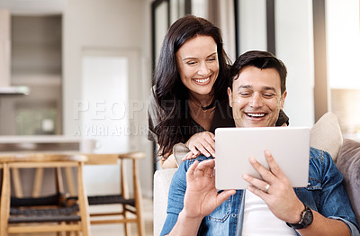 Buy stock photo Shot of a happy young couple using a digital tablet together at home