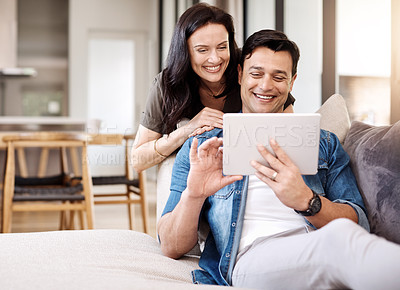 Buy stock photo Shot of a happy young couple using a digital tablet together at home