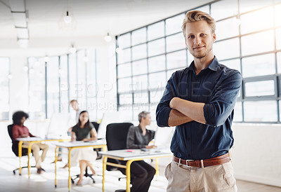 Buy stock photo Portrait of a happy designer posing in the office while his colleagues work in the background