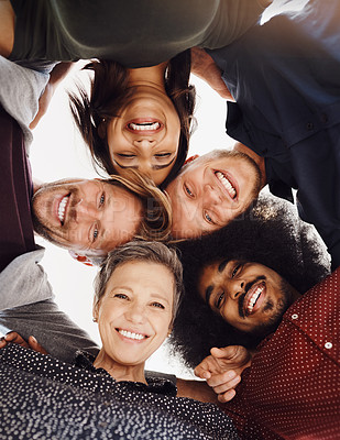 Buy stock photo Low angle portrait of a team of happy designers posing with their heads in a huddle in the office