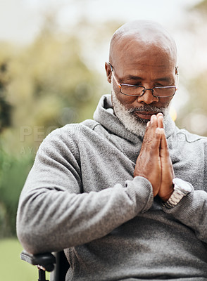 Buy stock photo Shot of a senior man holding his hands together in prayer while sitting in his wheelchair outside