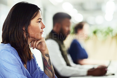 Buy stock photo Shot of a young designer working in an office with her colleagues in the background