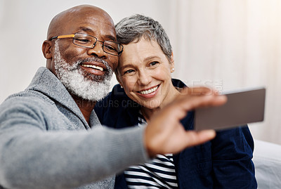 Buy stock photo Shot of an affectionate senior couple taking selfies while relaxing on the sofa at home