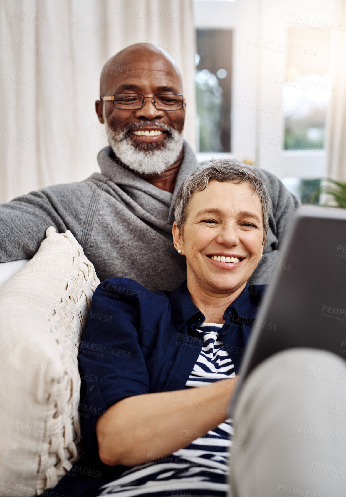 Buy stock photo Shot of an affectionate senior couple using a tablet while relaxing on the sofa at home