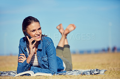 Buy stock photo Shot of an attractive young woman using a mobile phone while relaxing in the park