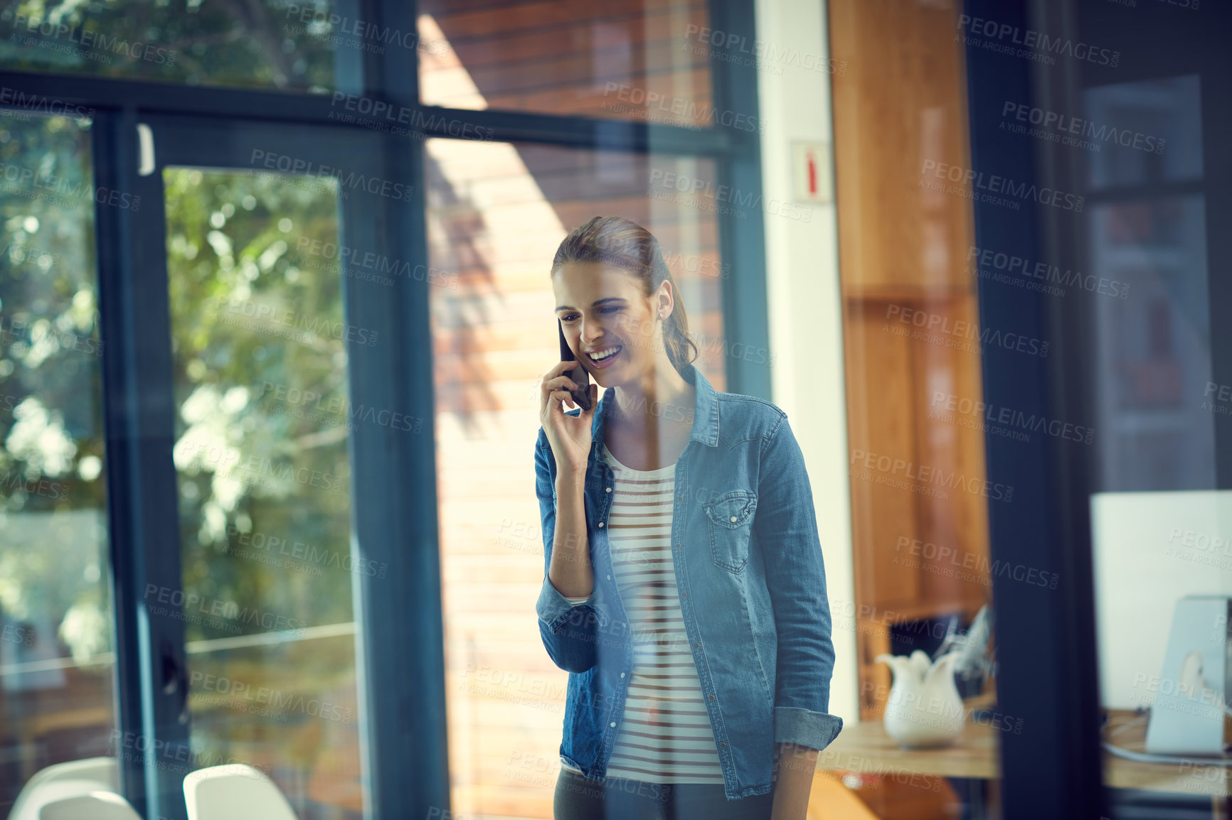 Buy stock photo Shot of a young businesswoman using a mobile phone in a modern office