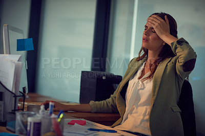 Buy stock photo Shot of a young businesswoman looking stressed while working late at the office