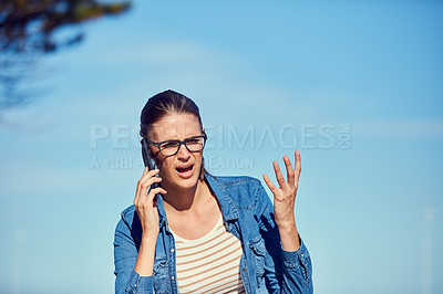 Buy stock photo Shot of an attractive young woman using a mobile phone outdoors and looking angry