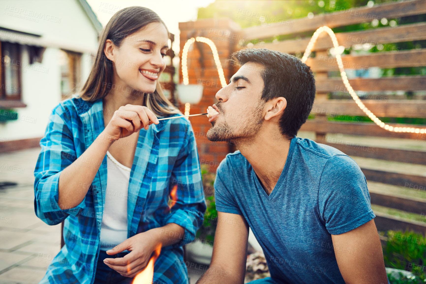 Buy stock photo Feeding, marshmallow and playful with couple at party together for barbecue, celebration or love. Biting, eating or flirting with happy man and woman outdoor for bonding, relationship or romance