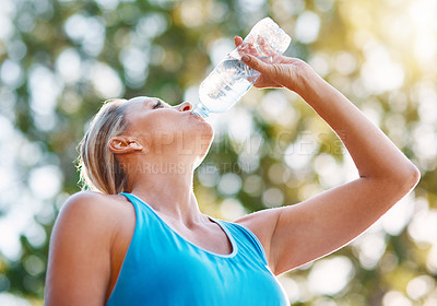 Buy stock photo Low angle shot of a mature woman drinking water out of a bottle outdoors