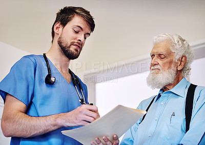 Buy stock photo Shot of a young doctor going through medical records with a senior patient at a hospital