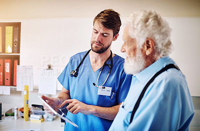 Buy stock photo Shot of a young doctor using a digital tablet to explain a diagnostic to a senior patient at a clinic