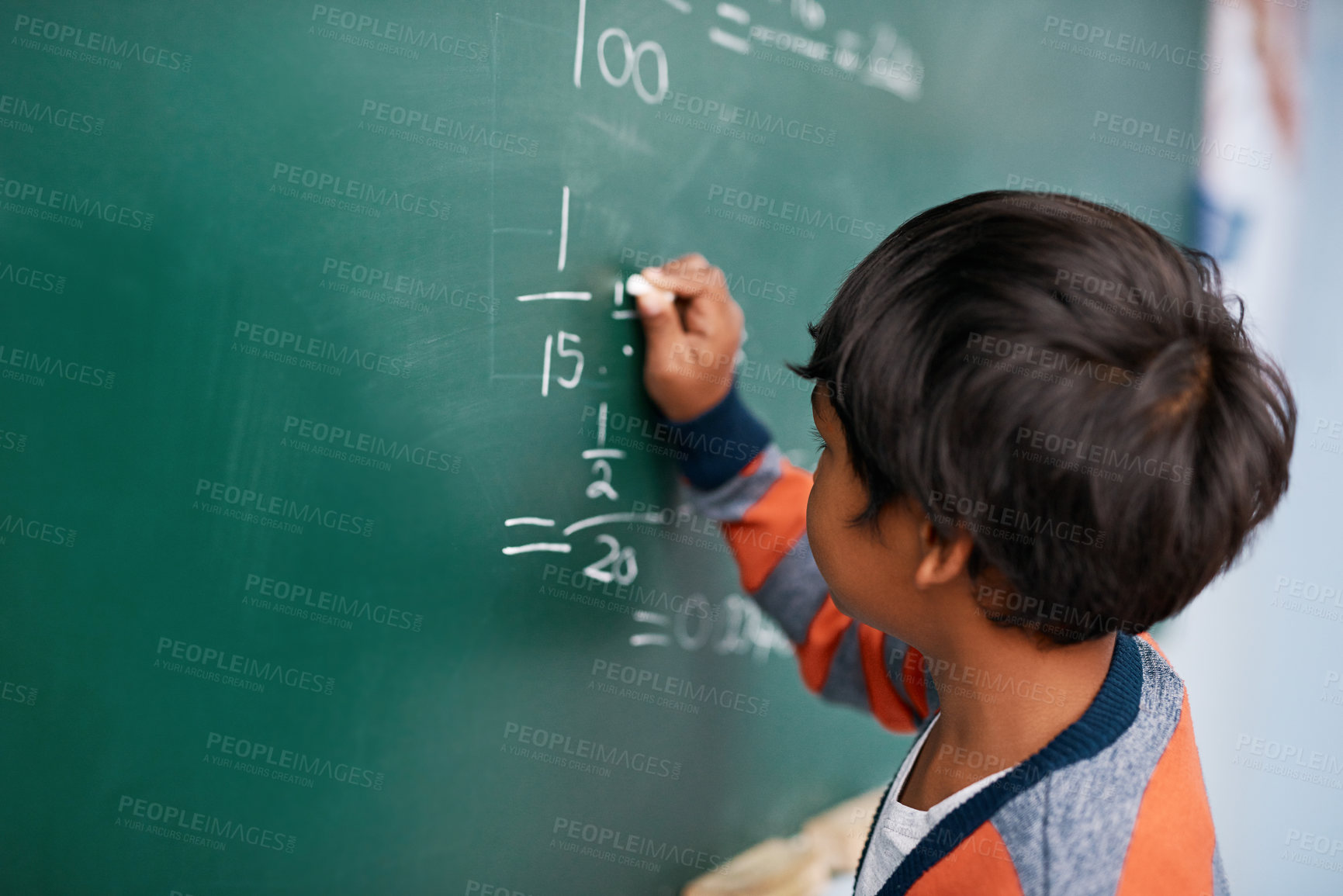 Buy stock photo Cropped shot of a focussed young elementary school kid writing answers to math questions on a green chalkboard in the classroom