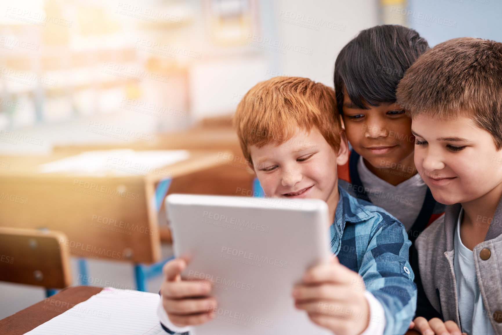 Buy stock photo Cropped shot of a group of elementary school children browsing on a digital tablet inside of the class during the day